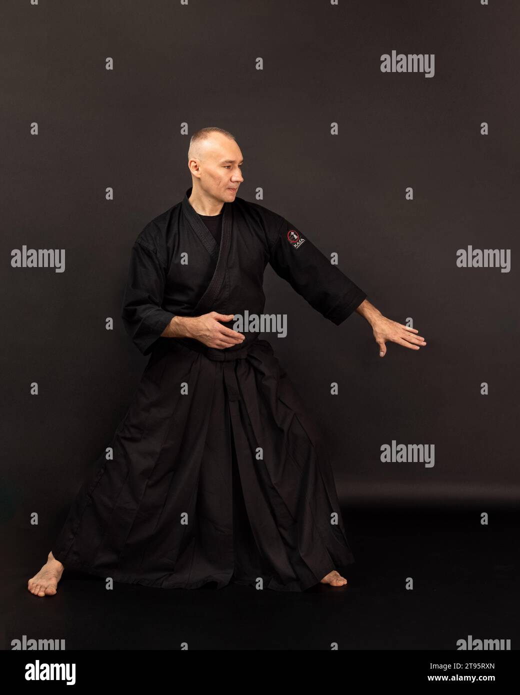 Ritratto del maestro aikido sensei con cintura sensei nera in kimono taekwondo su sfondo nero. Tradizionale samurai hakama kimono. Stile di vita sano Foto Stock