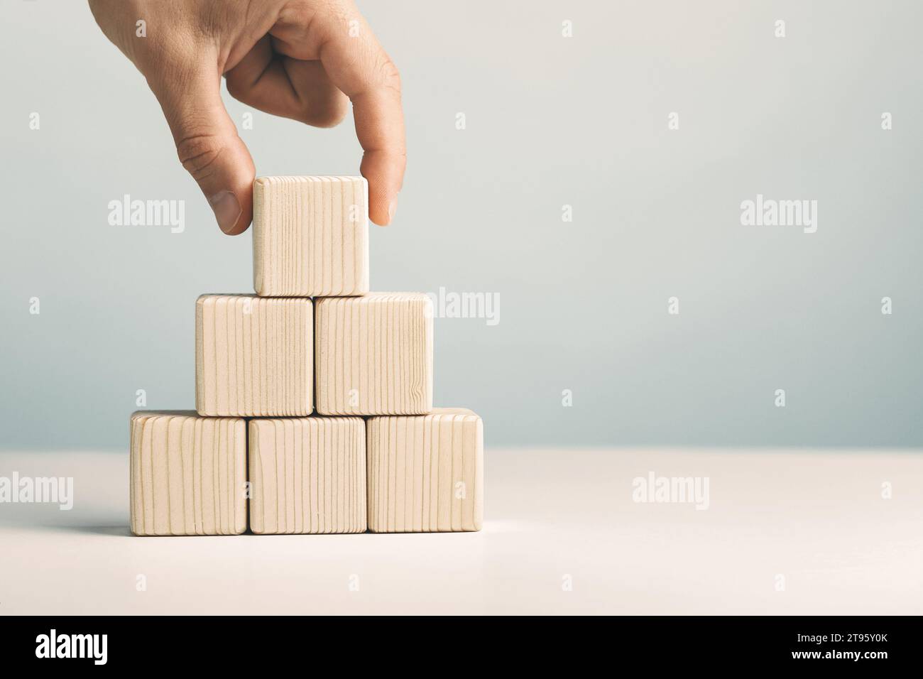 Inserimento a mano e impilamento di cubi di legno vuoti sul tavolo con spazio di copia per l'inserimento di testo o icona infografica. Foto Stock