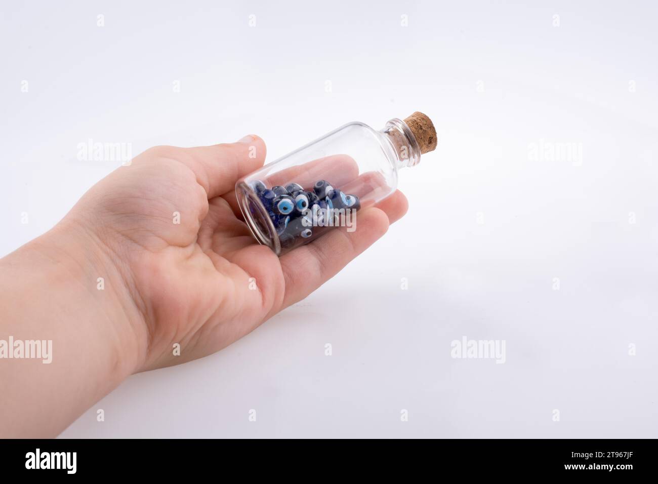 Piccola bottiglia di vetro con il perla dell'occhio malvagio blu in mano Foto Stock