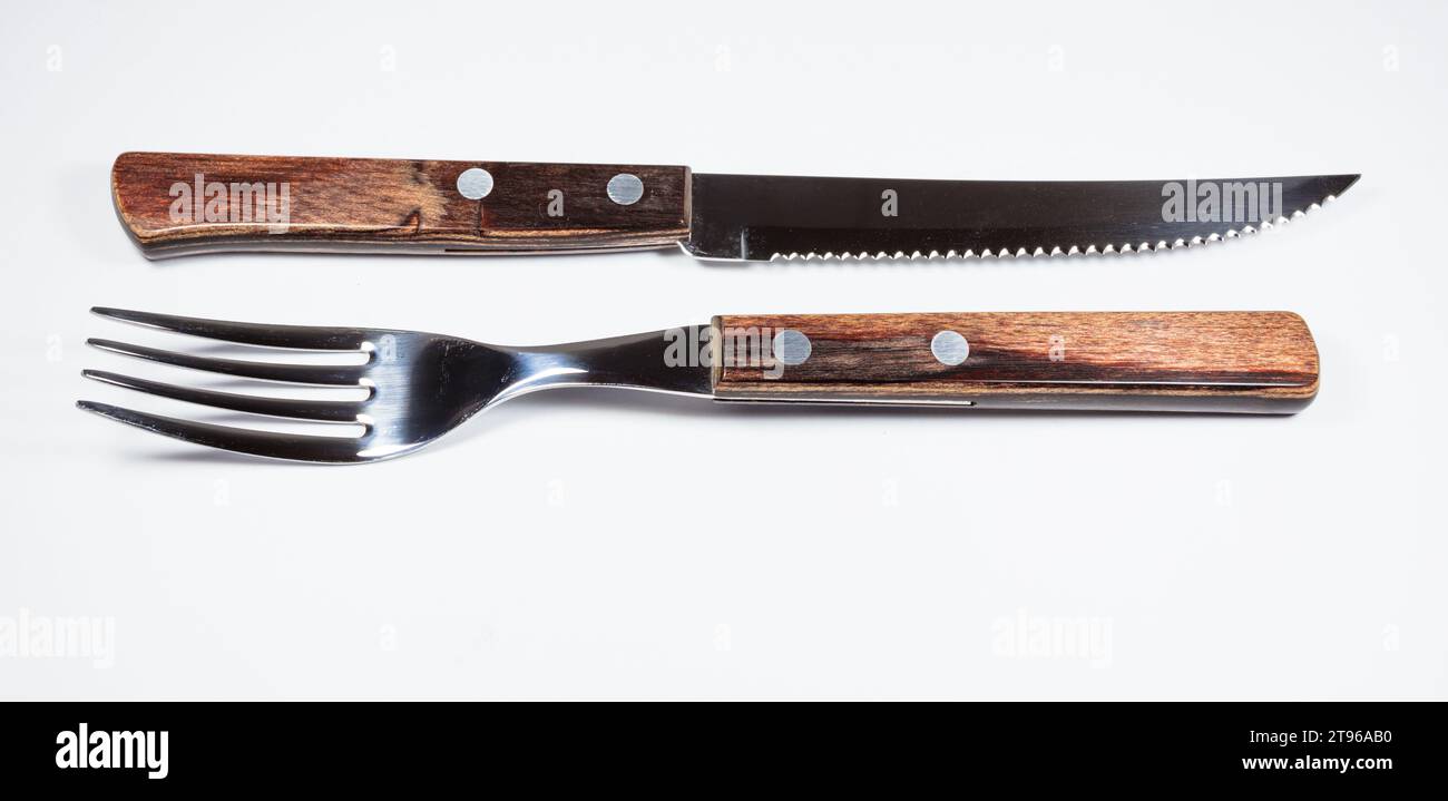 Primo piano di una forchetta e di un coltello con manici in legno su sfondo bianco. Foto Stock