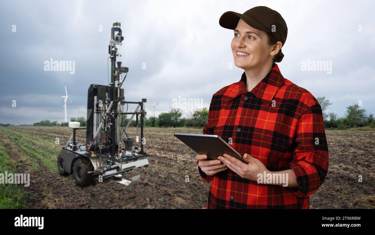 L'agricoltore controlla il robot autonomo per misurare la qualità del suolo in un campo agricolo. Concetto di agricoltura intelligente.. Foto Stock