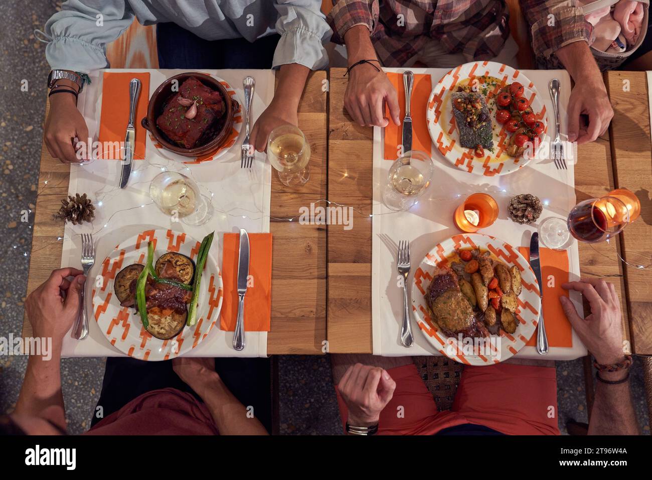 Da sopra gruppo di raccolto anonimo seduti a tavola con piatti deliziosi assortiti e bevande alcoliche durante la cena nel ristorante Foto Stock