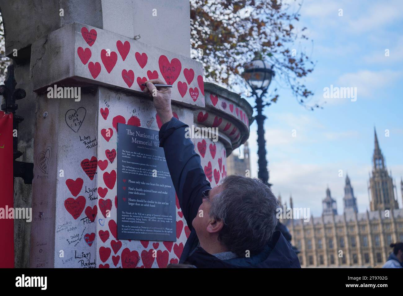 Londra, Regno Unito. 23 novembre 2023. Un membro della famiglia scrive su un cuore dipinto al National Covid Memorial Wall. Il governo è stato criticato dall' inchiesta sulla covid per aver preso decisioni e non essere stato bloccato in precedenza . Crediti: amer ghazzal/Alamy Live News Foto Stock