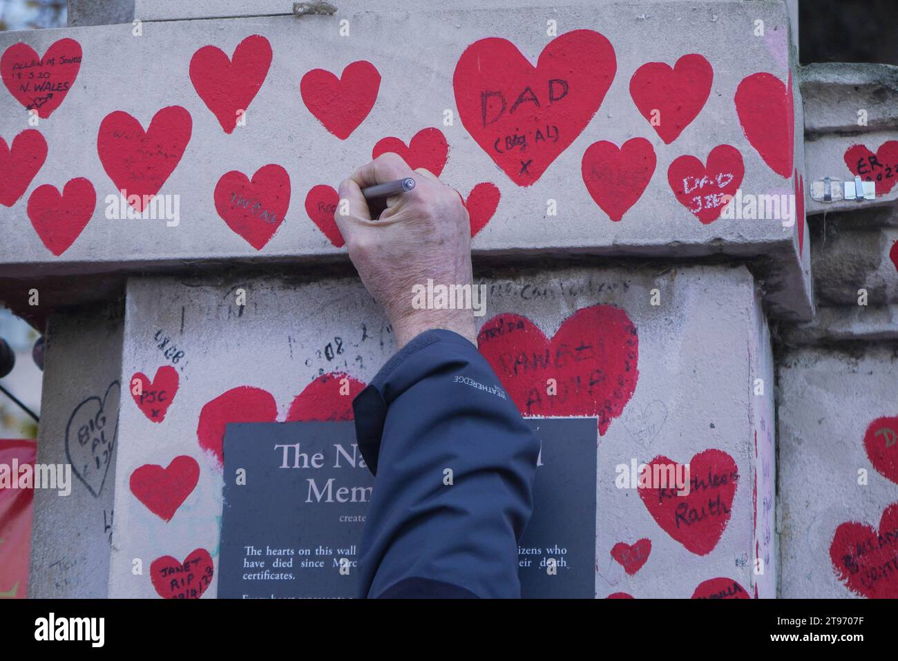 Londra, Regno Unito. 23 novembre 2023. Un membro della famiglia scrive un messaggio su un cuore dipinto al National Covid Memorial Wall. Il governo è stato criticato dall' inchiesta sulla covid per aver preso decisioni e non essere stato bloccato in precedenza . Crediti: amer ghazzal/Alamy Live News Foto Stock
