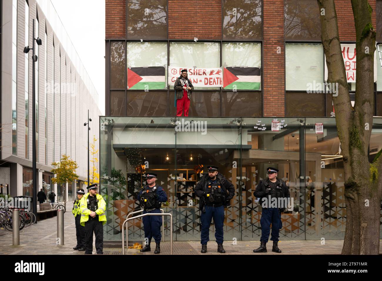 Protesta pro Palestina contro il proprietario della Elbit Systems Fisher German. Manifestante sul tetto di Centurion House con la polizia allineata davanti. Manchester Regno Unito Foto Stock