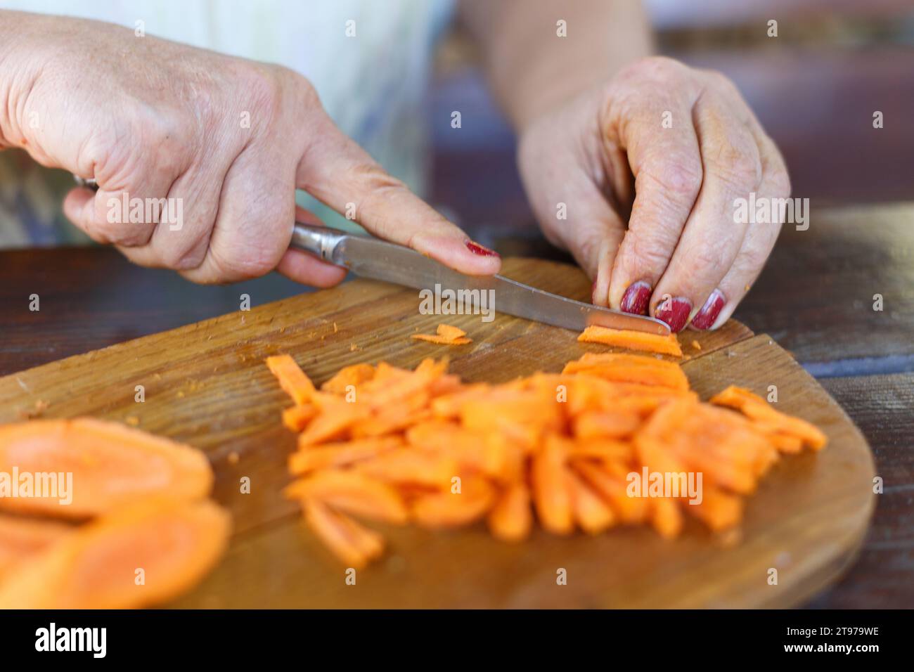 Donna taglia carota. Le carote fresche per bambini sbucciate organiche si  avvicinano sul tagliere del tavolo da cucina bianco Foto stock - Alamy