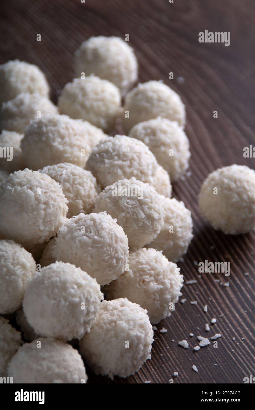 In questa allettante foto, un primo piano di palle gourmet di cocco ruba i riflettori su uno sfondo scuro. Il fascino rotondo e dolce rende queste t Foto Stock