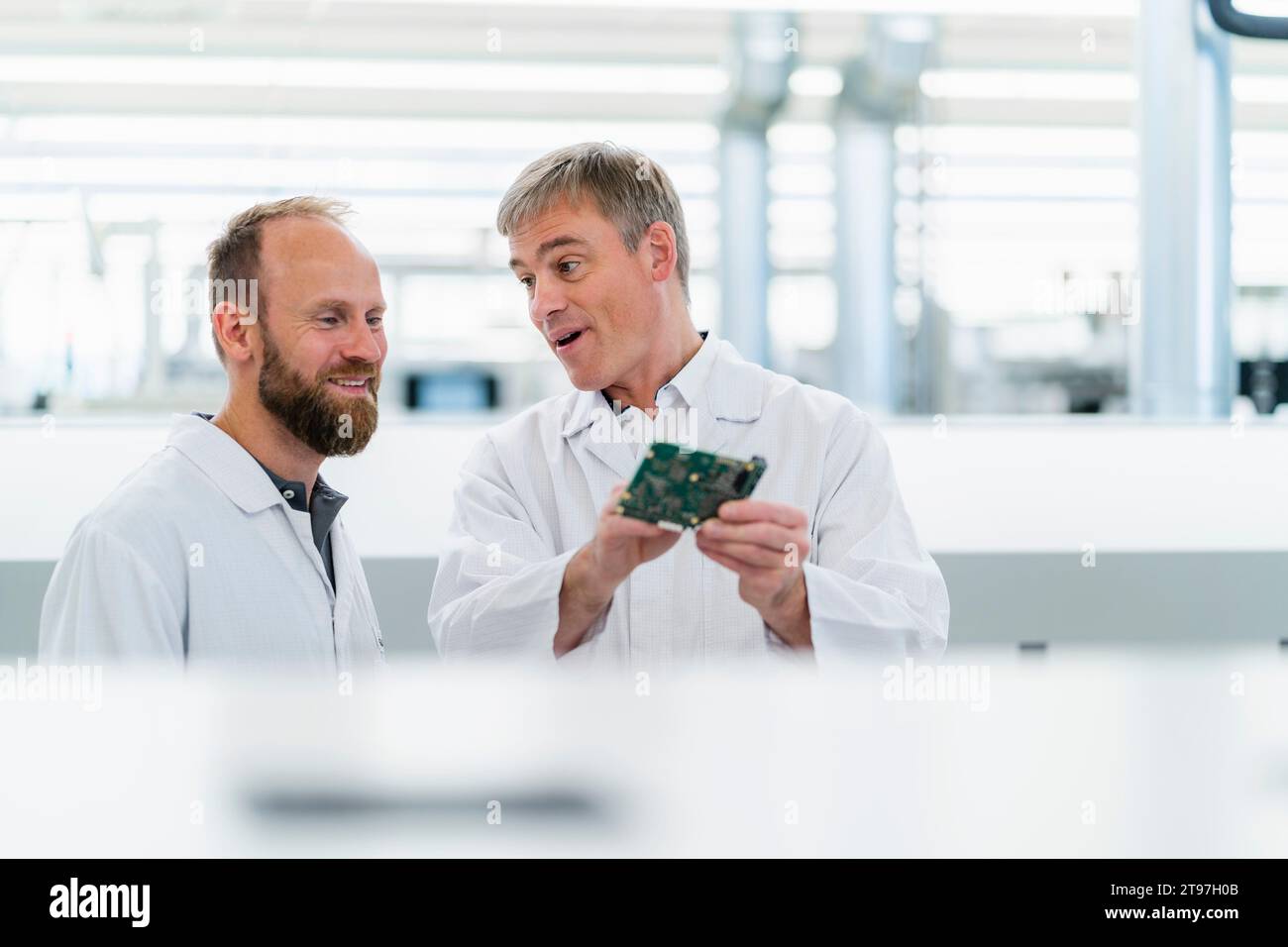 Tecnici elettrici che controllano la scheda madre in fabbrica di elettronica Foto Stock