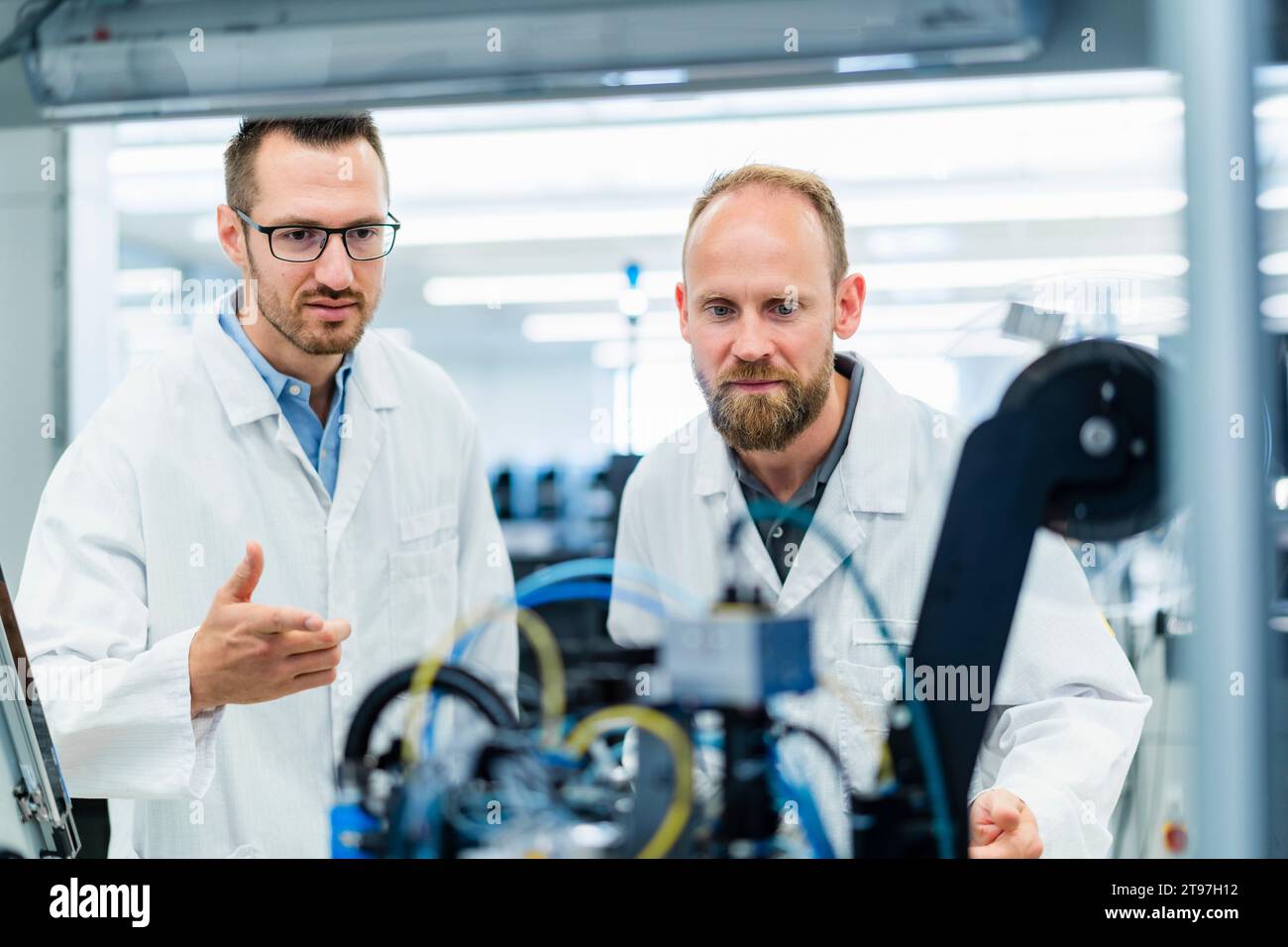 Colleghi di fabbrica di elettronica che guardano il lavoro delle macchine Foto Stock