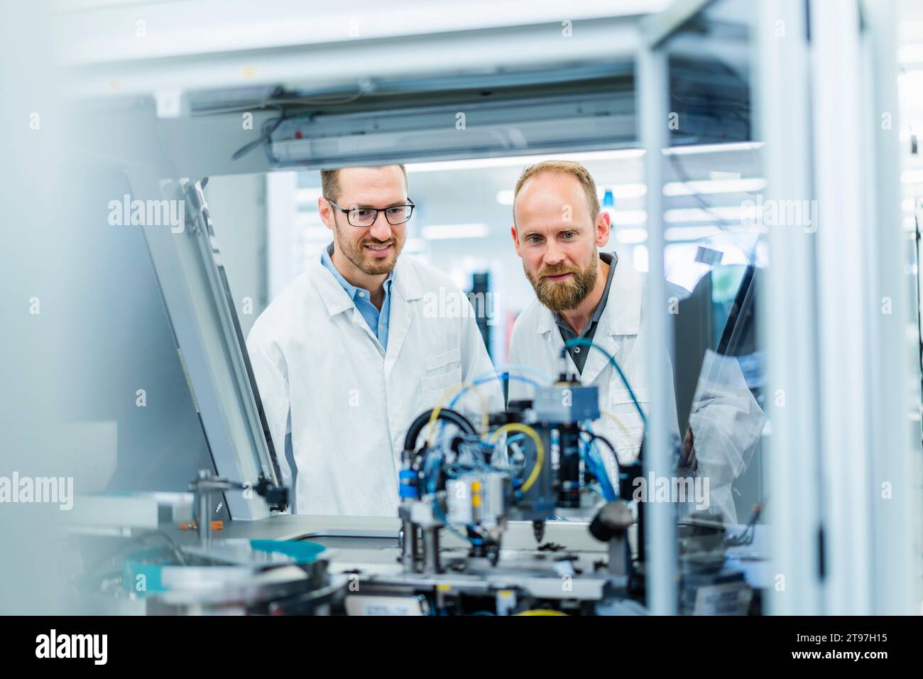 Colleghi di fabbrica di elettronica che guardano il lavoro delle macchine Foto Stock
