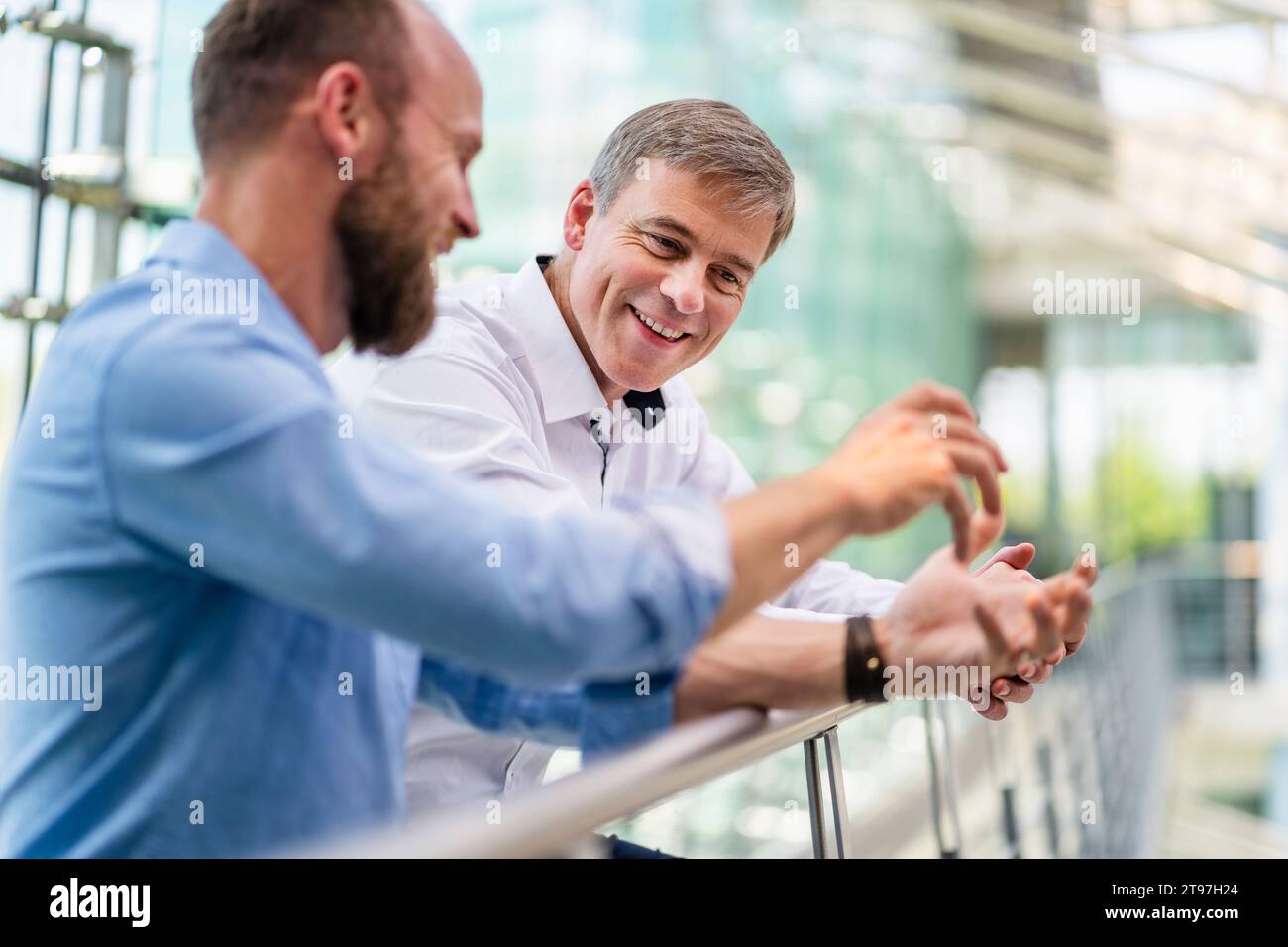 Colleghi che discutono di soluzioni aziendali innovative che si appoggiano in piedi nei corridoi degli uffici Foto Stock