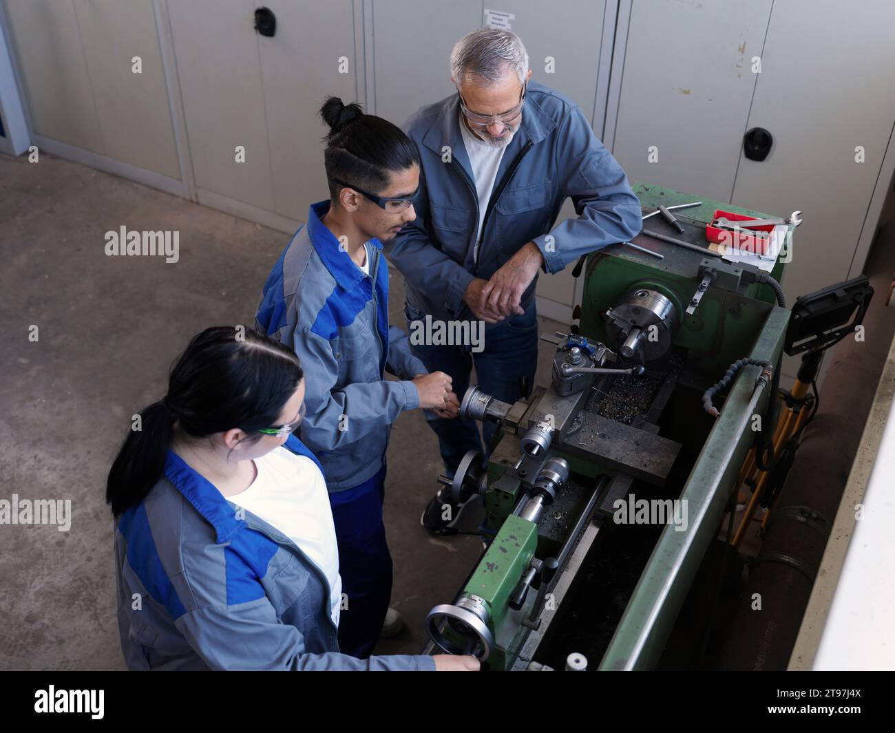 Apprendisti che apprendono la macchina del tornio con l'istruttore in officina Foto Stock