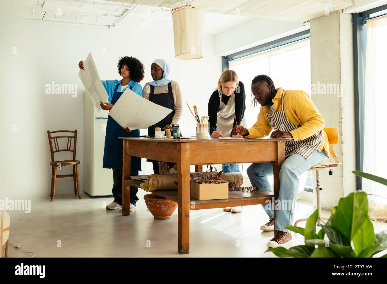 Artisti che lavorano e guardano i dipinti in studio Foto Stock