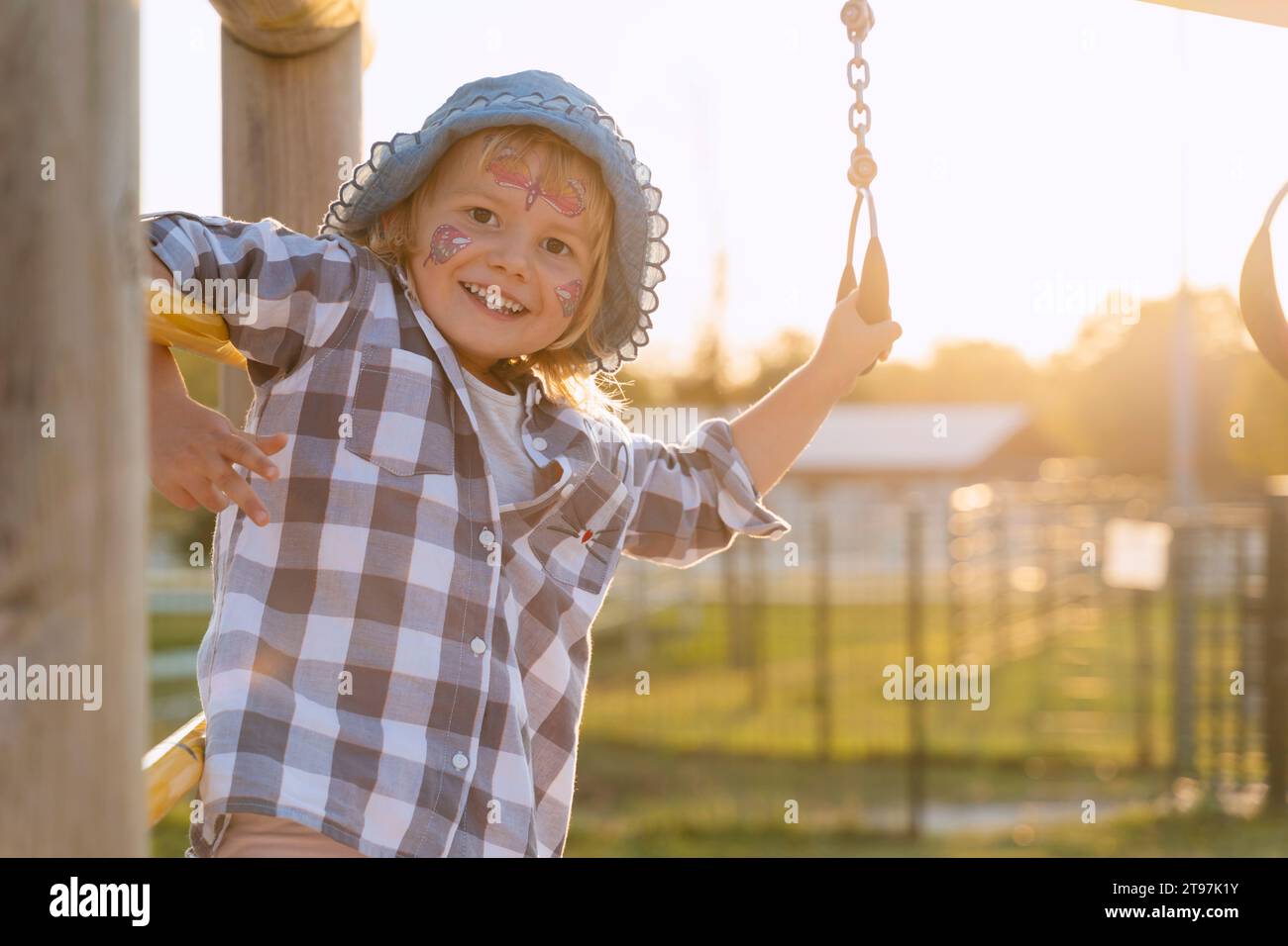 Ragazza sorridente con il viso che gioca nel parco giochi al tramonto Foto Stock