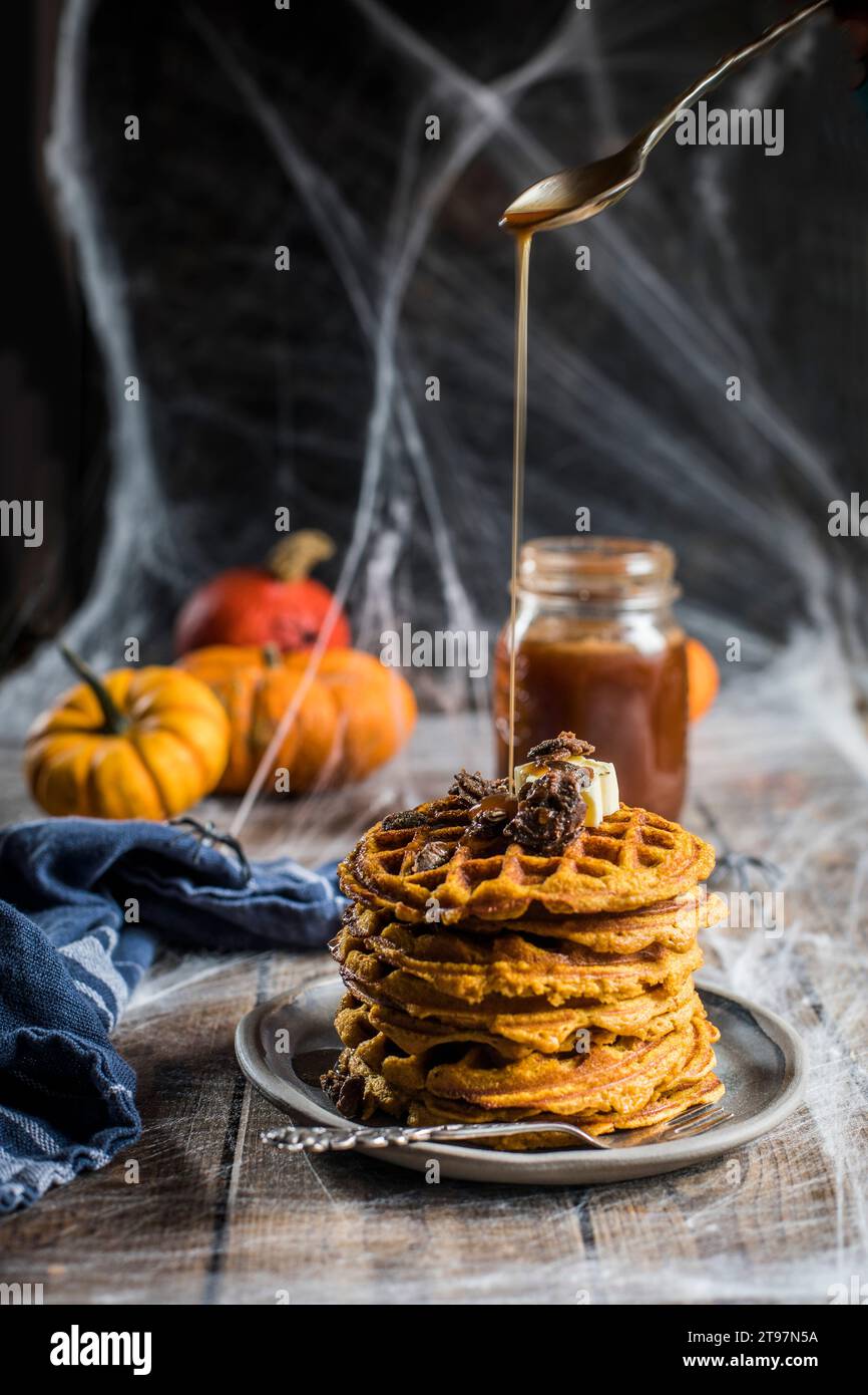 Sciroppo versato su una pila di cialde fatte in casa con spezie di zucca e semi caramellati Foto Stock