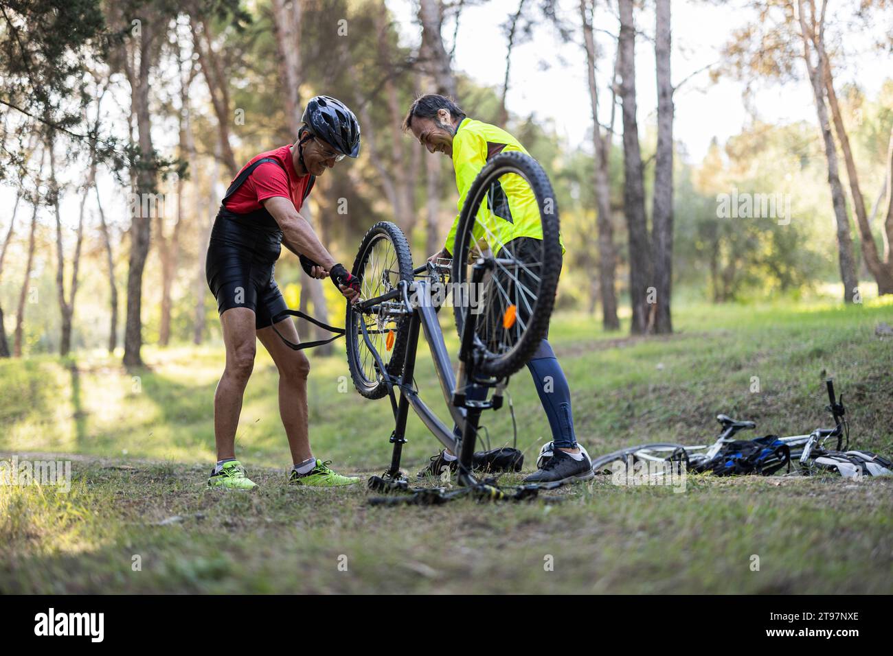 Amici felici che riparano la bicicletta nella foresta Foto Stock