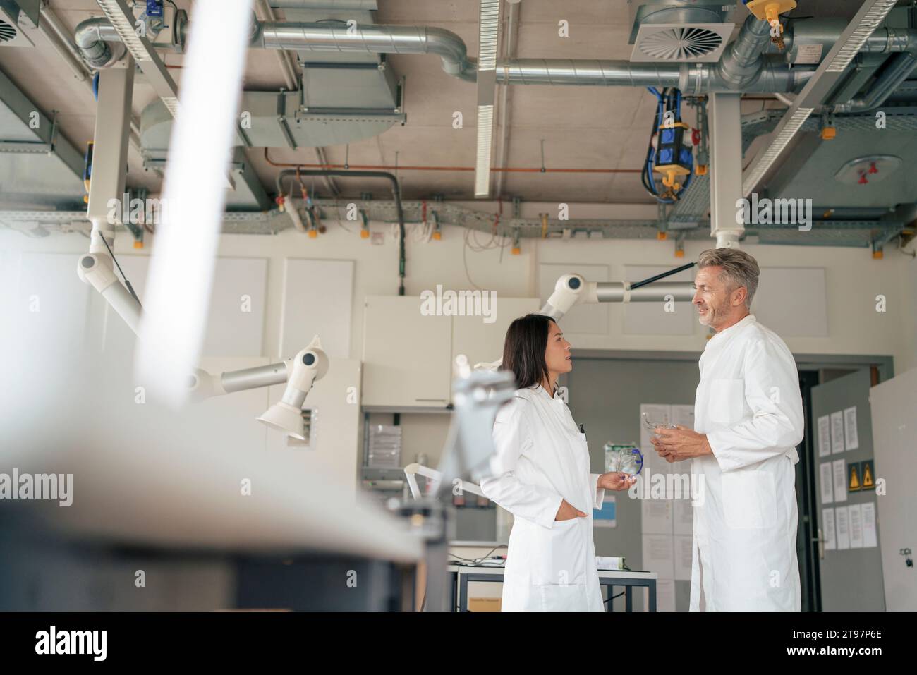 Scienziati che discutono in laboratorio vicino a bracci robotici Foto Stock