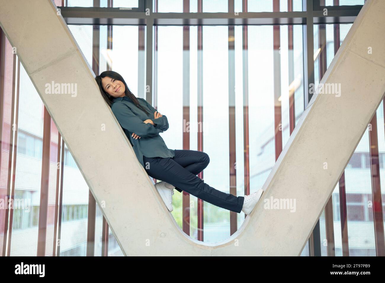 Felice donna d'affari appoggiata alla colonna architettonica Foto Stock