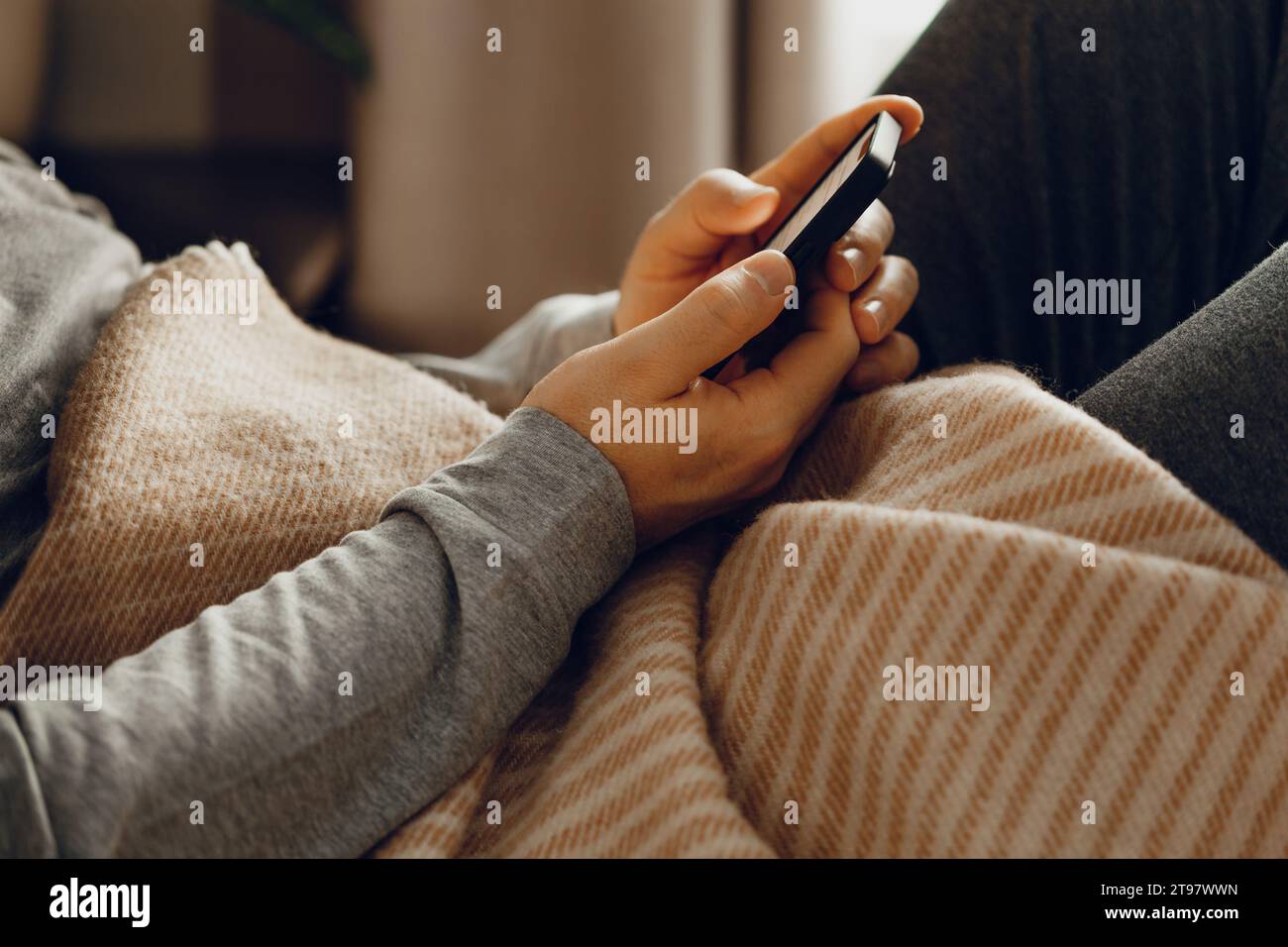 un uomo caucasico rilassante, utilizzando smartphone sdraiato a letto sotto tiro a casa Foto Stock