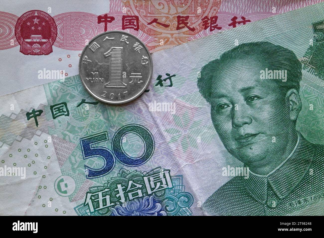 Una moneta da 1 yuan sopra una banconota da 50 yuan e una banconota da 100 yuan. Foto Stock