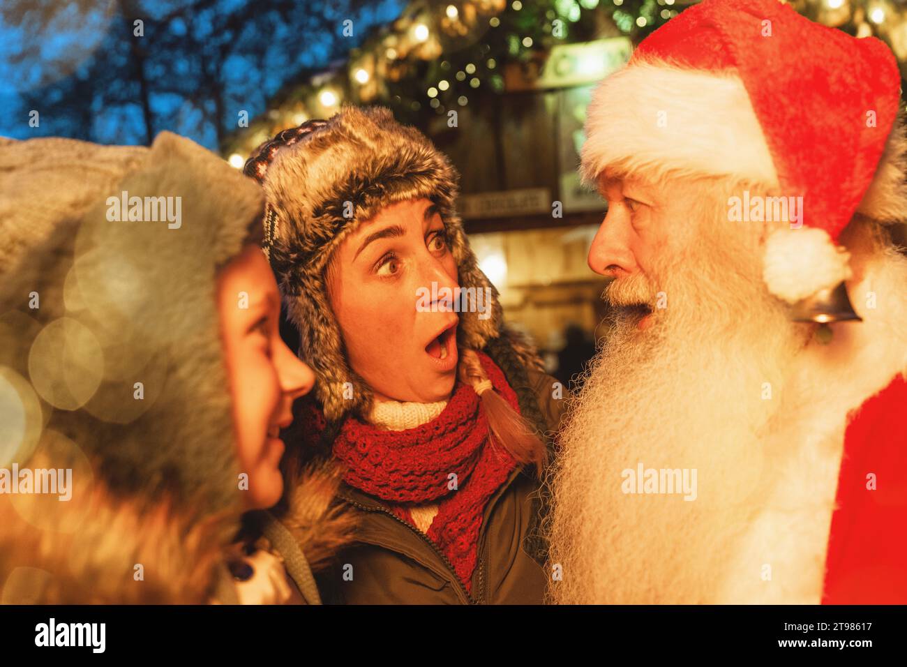 Donna e bambino sotto shock e gioia che incontrano Babbo Natale in un mercatino di Natale Foto Stock