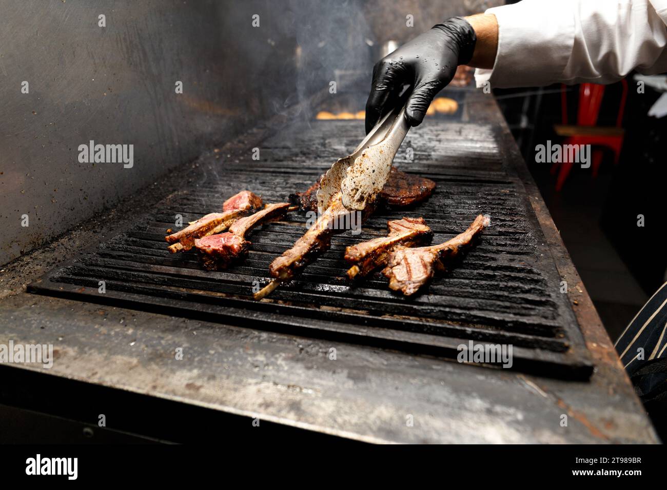 Appetitose bistecche di ribeye e filetti disposti sulla griglia su una fiamma durante la cottura alla griglia. Lo chef prepara bistecche di tomahawk alla griglia. Foto Stock