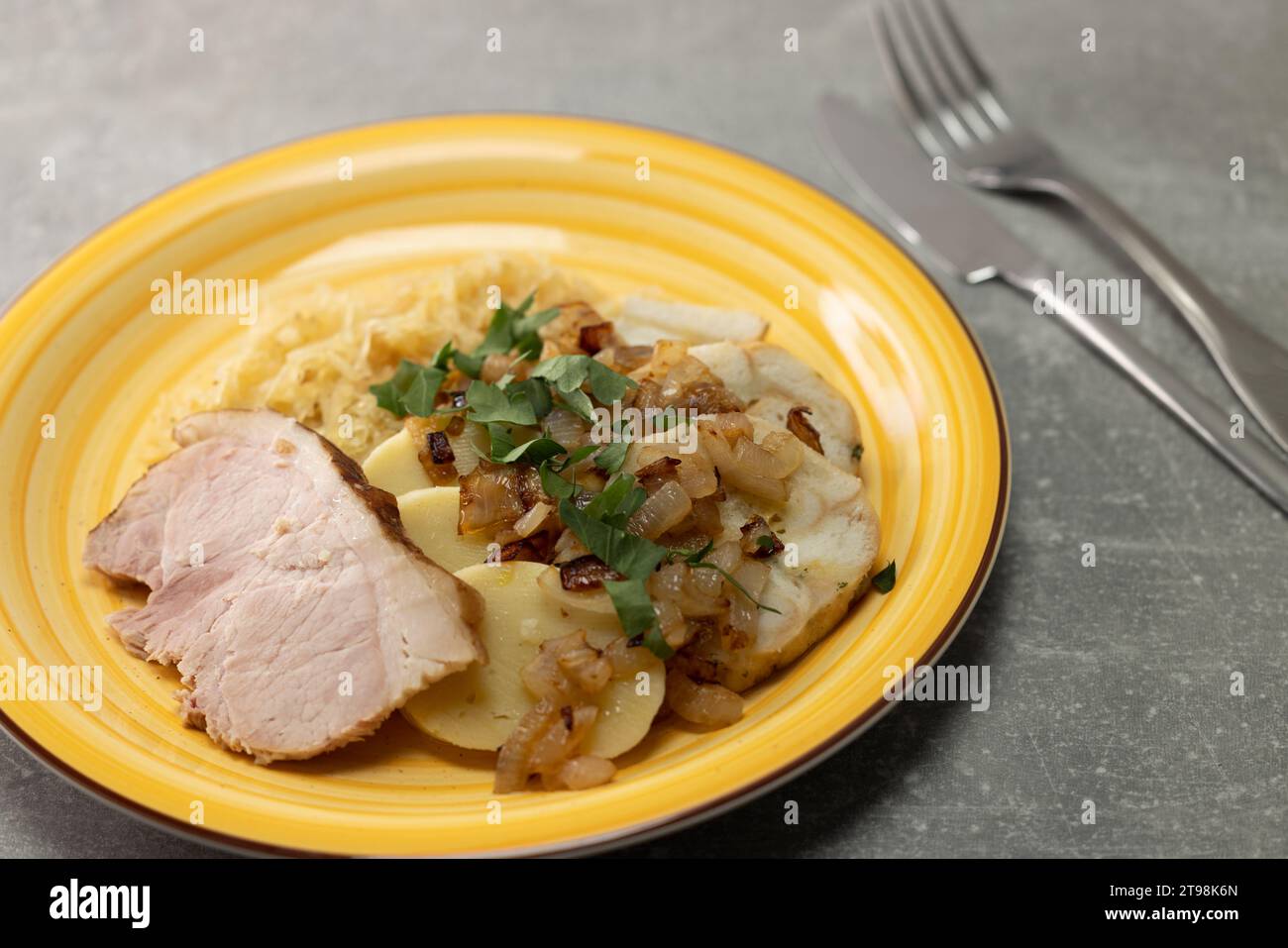 carne di maiale con gnocchi di patate e cavolo sottaceto servito con cipolla arrosto Foto Stock