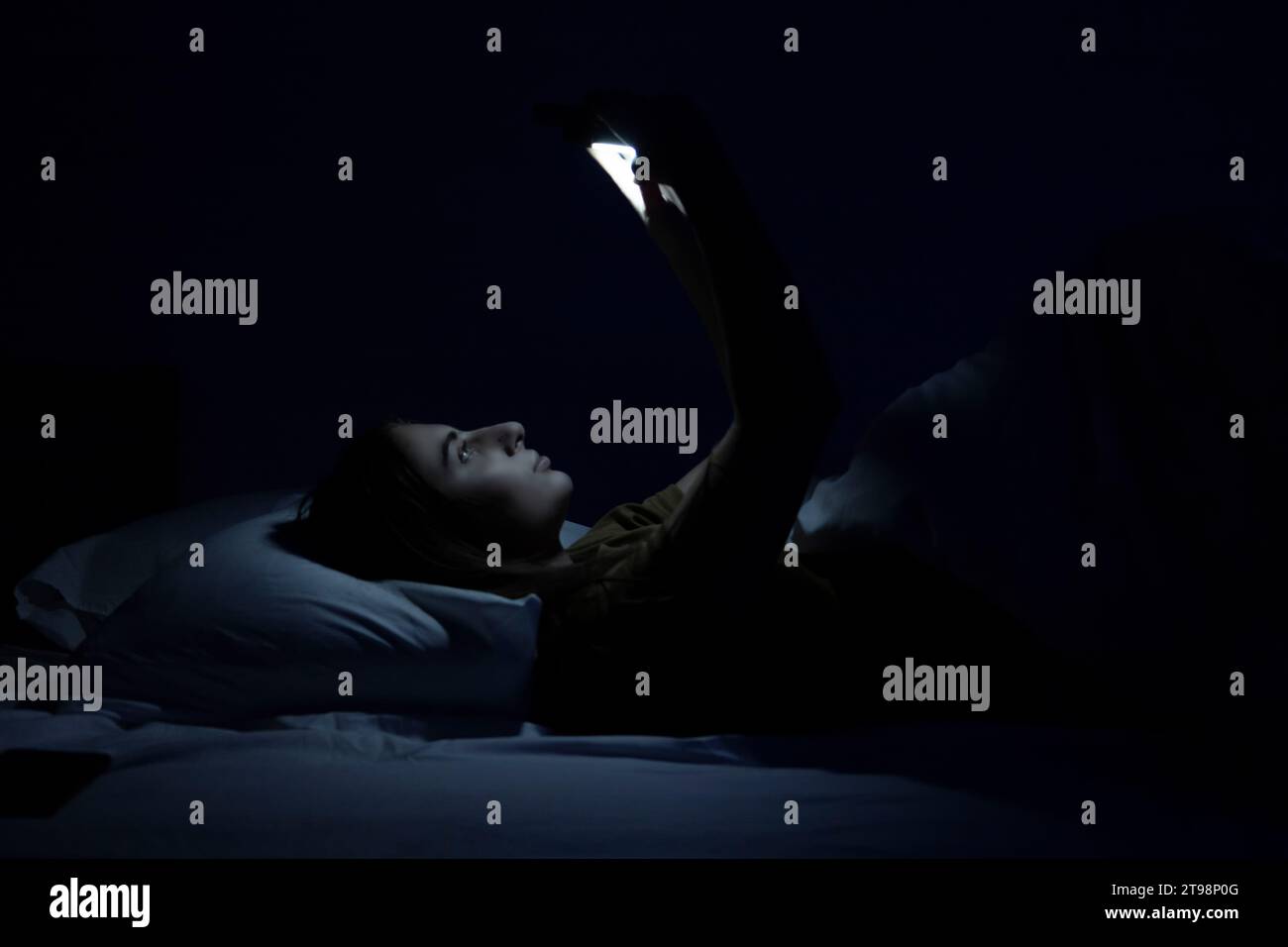 bellissima ragazza a letto con letto bianco e telefono. Foto Stock