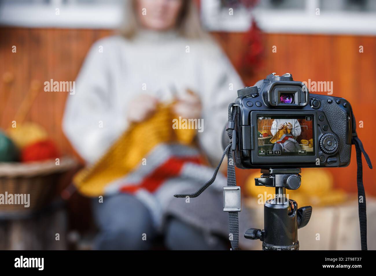 Donna che registra su una videocamera un video tutorial o un blog sulla tecnica della lavorazione a maglia della lana. Influencer Teaching ed e-learning online Foto Stock