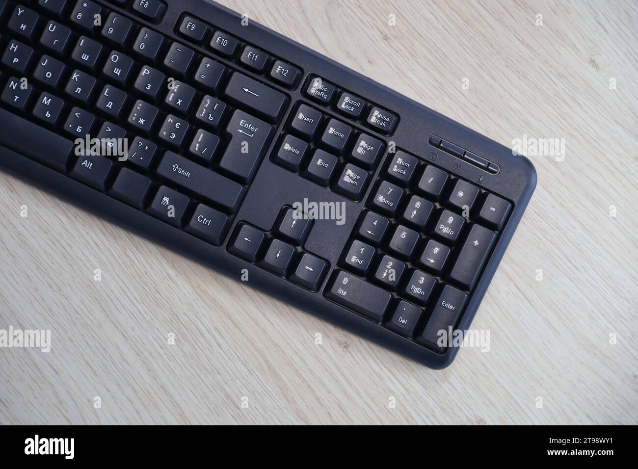 Piccola tastiera nera compatta per computer di gioco su un tavolo realizzata con tavole di legno di pino. Tastiera wireless con interruttori meccanici per gadget e computer. Copia spazio Foto Stock