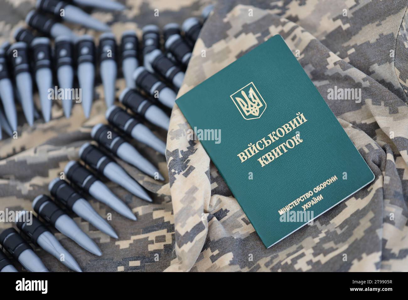 Documento d'identità militare ucraino su tessuto con trama mimetica pixeled. Panno con motivo camouflage in pixel grigio, marrone e verde con gettone personale dell'esercito ucraino e cintura di proiettili mitragliatrici Foto Stock