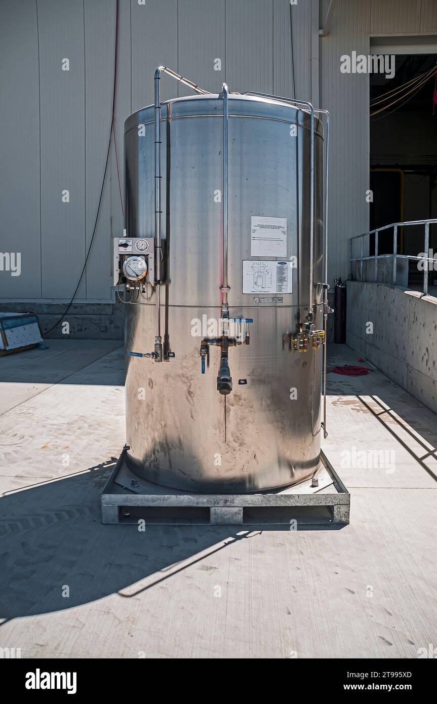 Un serbatoio in acciaio inox, all'aperto su un pallet metallico in un magazzino di refrigerazione industriale a CO2 (stoccaggio a freddo) in costruzione. Foto Stock