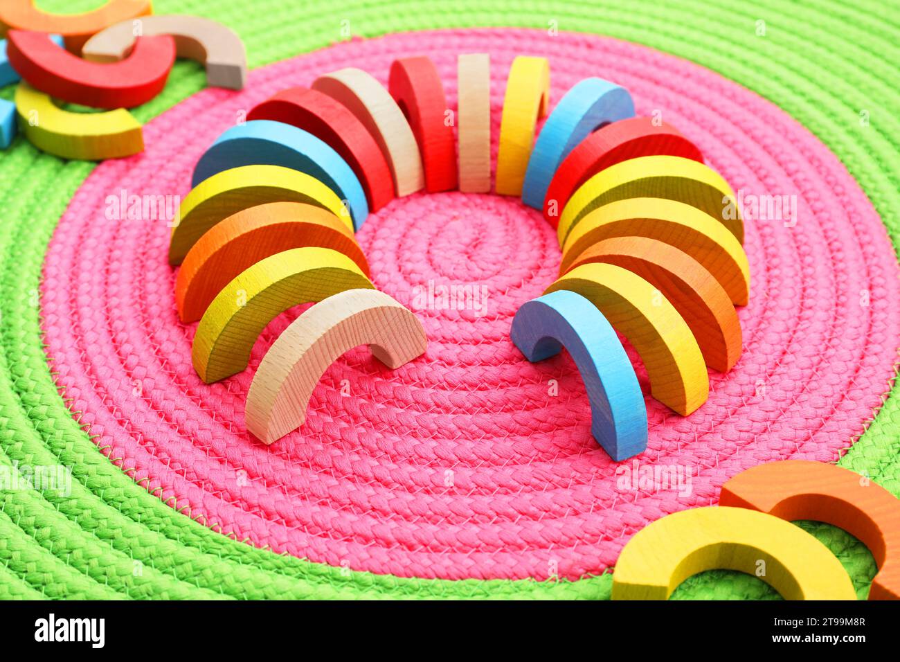 Coloratissimi pezzi di legno su tappetino colorato. Giocattolo educativo per lo sviluppo di abilità motorie Foto Stock