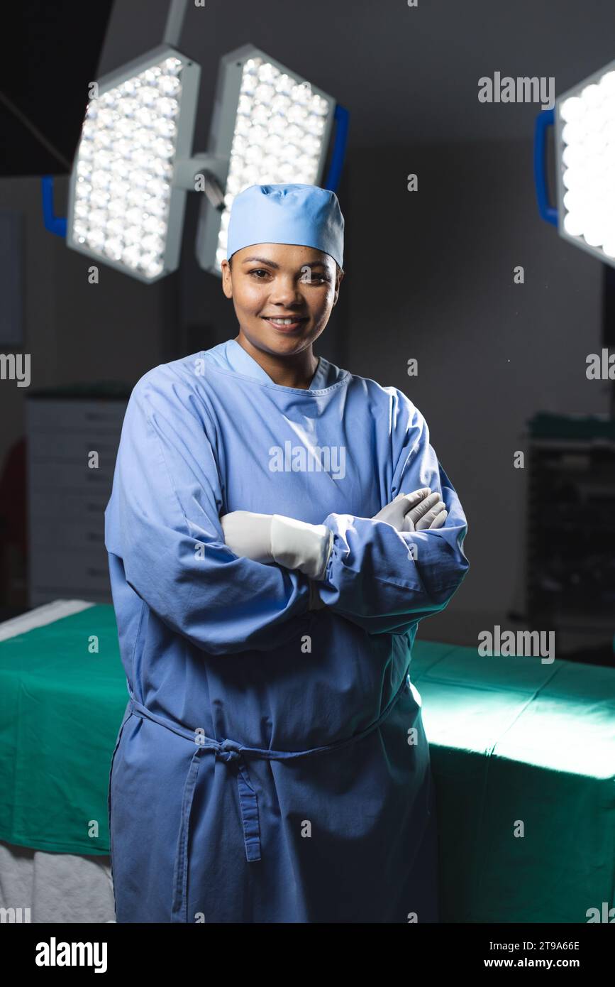 Ritratto di felice chirurgo birazziale che indossa un abito chirurgico in sala operatoria. Medicina, sanità, chirurgia, lavoro e ospedale, inalterati. Foto Stock