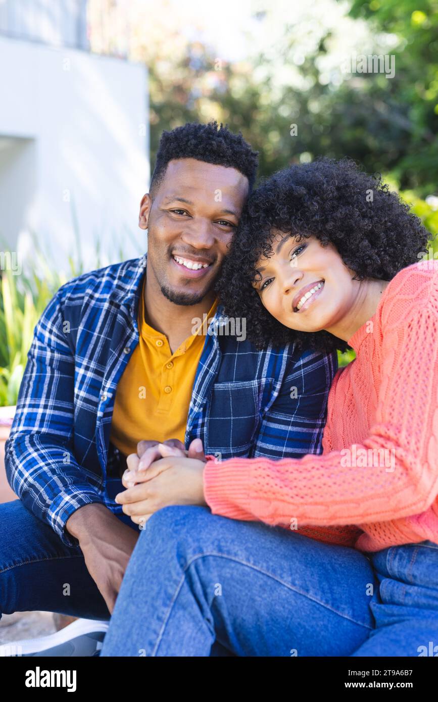 Felice coppia afro-americana che abbraccia e tiene per mano le scale nel giardino soleggiato, spazio per le copie. All'aperto, espressione, gesticolazione, amore, insieme Foto Stock