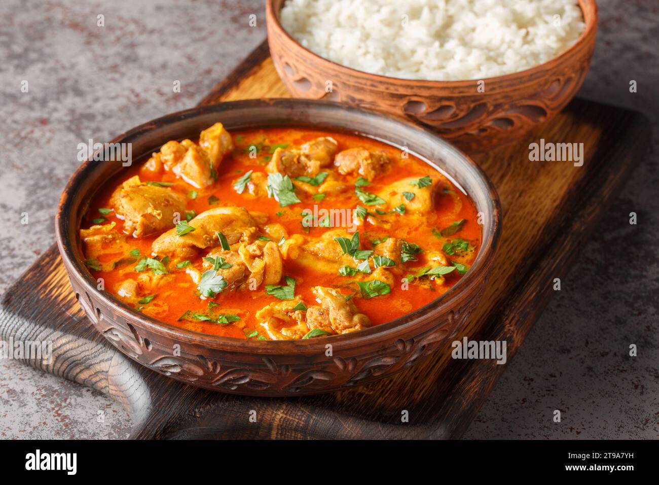 Il pollo lahori è un tradizionale curry pakistano di pollo proveniente dalla città di Lahore, servito con primo piano di riso sul tavolo di legno. Hor Foto Stock