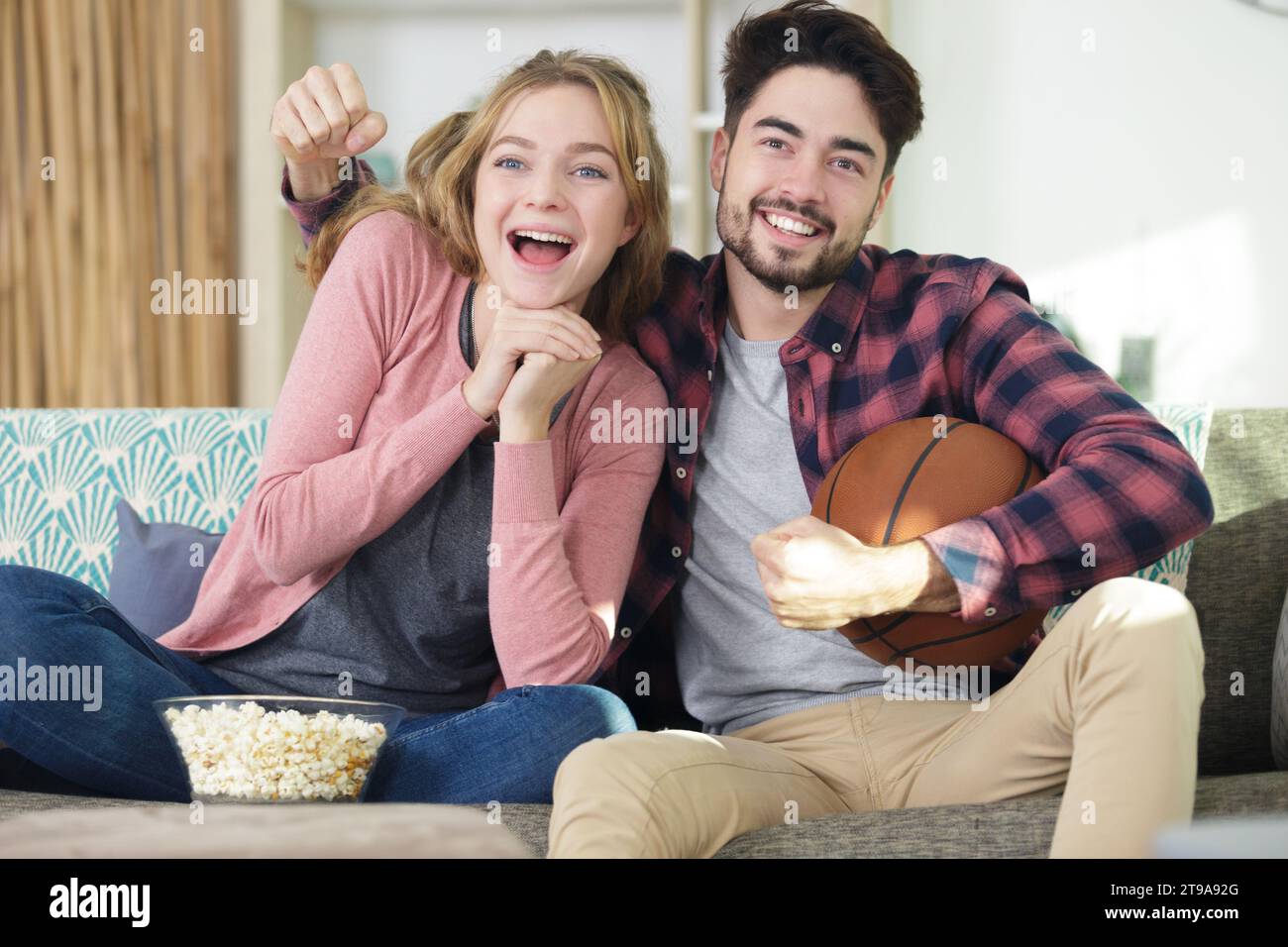 coppia che si diverte a guardare una partita di basket in televisione Foto Stock