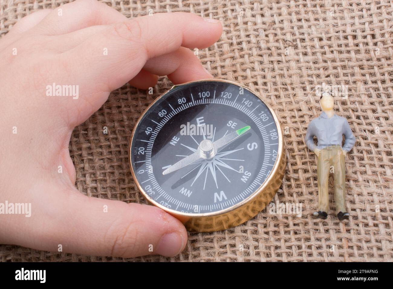 Mano che tiene una bussola accanto a una figurina Foto Stock