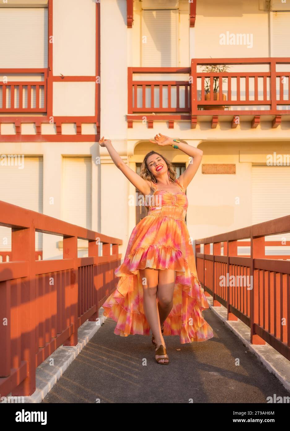 Foto verticale di una donna che balla felicemente con un lungo abito durante il tramonto all'aperto Foto Stock