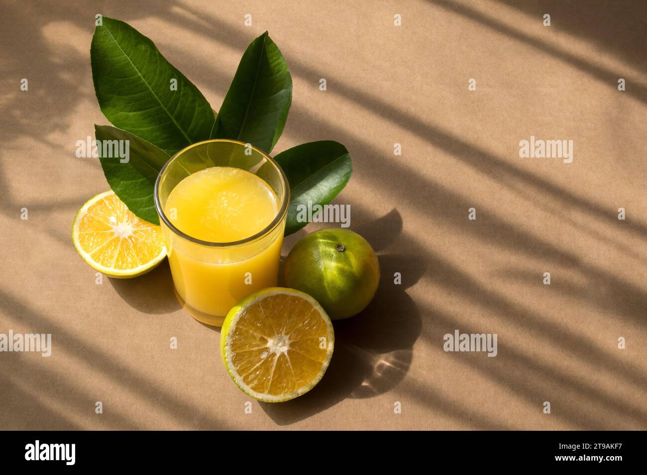 Un succo d'arancia, foglie e frutta con uno sfondo rustico e spazio per il testo sul lato destro Foto Stock