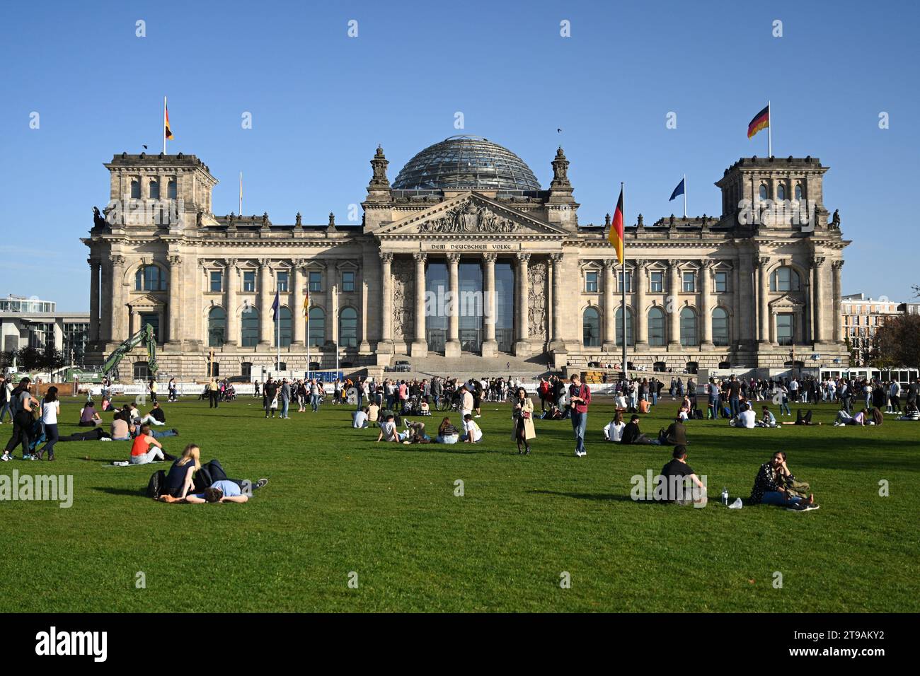 Berlino, Germania - 30 ottobre 2022: La gente si rilassa sul gras vicino al Bundestag tedesco (edificio del Reichstag) è il parlamento nazionale della federazione Foto Stock