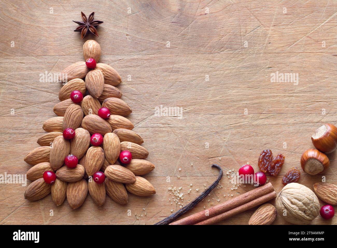 Albero di Natale fatto di mandorle decorate con mirtilli rossi su fondo di legno, concetto di cibo natalizio Foto Stock