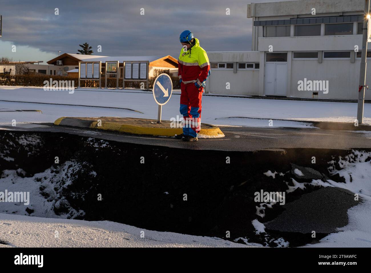 Grindavik, Islanda. 23 novembre 2023. Un membro della squadra di emergenza guarda la fessura aperta nel terreno. Anche se la probabilità di un'eruzione vulcanica è stata ridotta, è ancora possibile. La polizia e i servizi di emergenza del paese, in coordinamento con il governo, stanno permettendo ai residenti di Grindavik di entrare nella zona per finire di ritirare i loro effetti personali prima che le case e le imprese siano sigillate. Potrebbero volerci mesi prima che i residenti tornino alle loro case, se questo finalmente succede. Credito: SOPA Images Limited/Alamy Live News Foto Stock