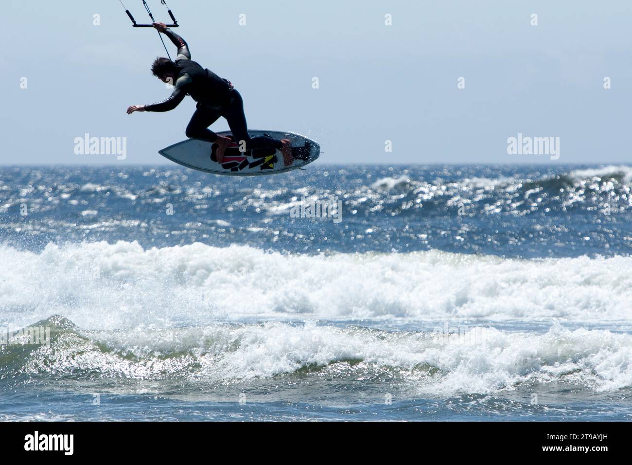 Silhouette di un kitesurfer maschio che salta fuori dal surf. Foto Stock
