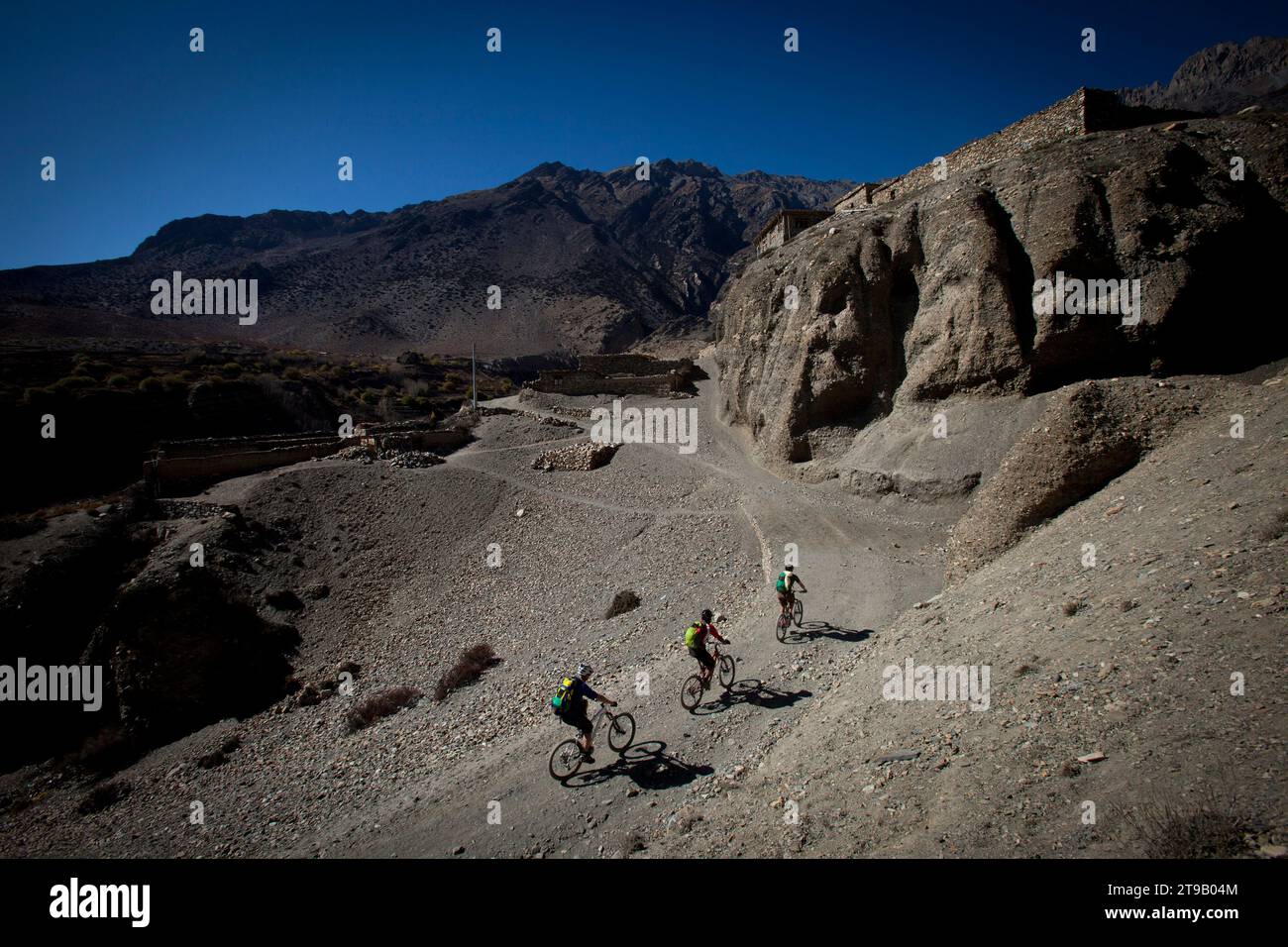 Tre uomini visti dall'alto cavalcano in mountain bike lungo una strada sterrata con vista sulle montagne. Foto Stock