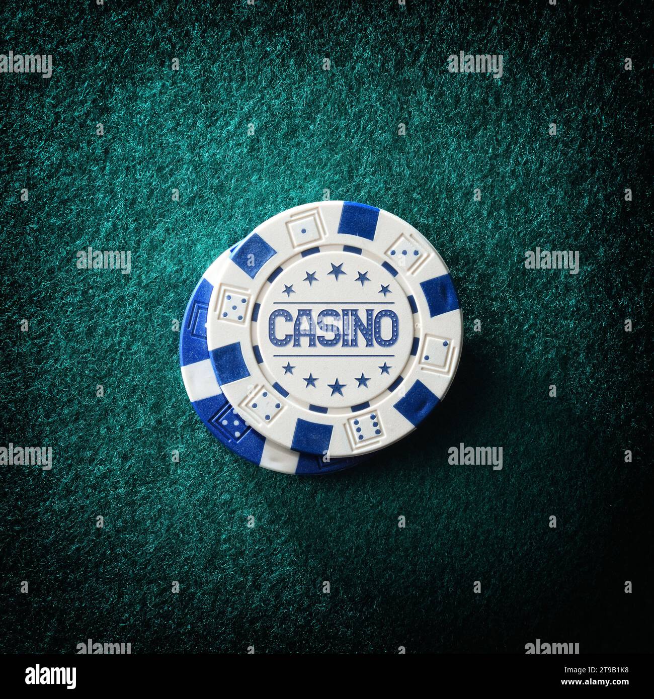 Carta da parati con chip di scommesse del casinò con testo che pubblicizza un casinò su un tappeto di feltro verde. Vista dall'alto. Composizione quadrata. Foto Stock