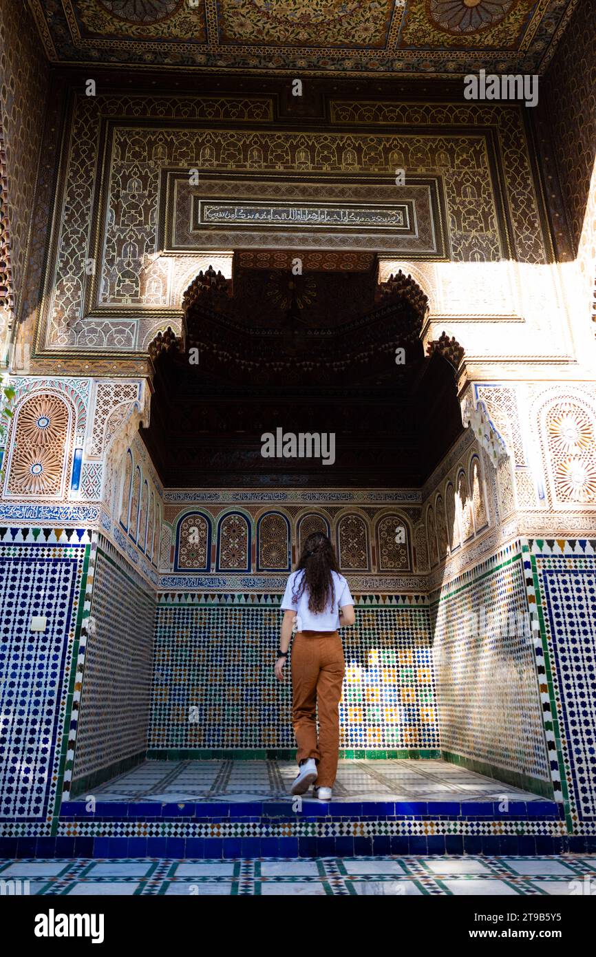 Splendida vista di una ragazza che visita il Palazzo Bahia durante una giornata di sole. Il Palazzo Bahia di Marrakech è un impressionante esempio di architettura marocchina Foto Stock