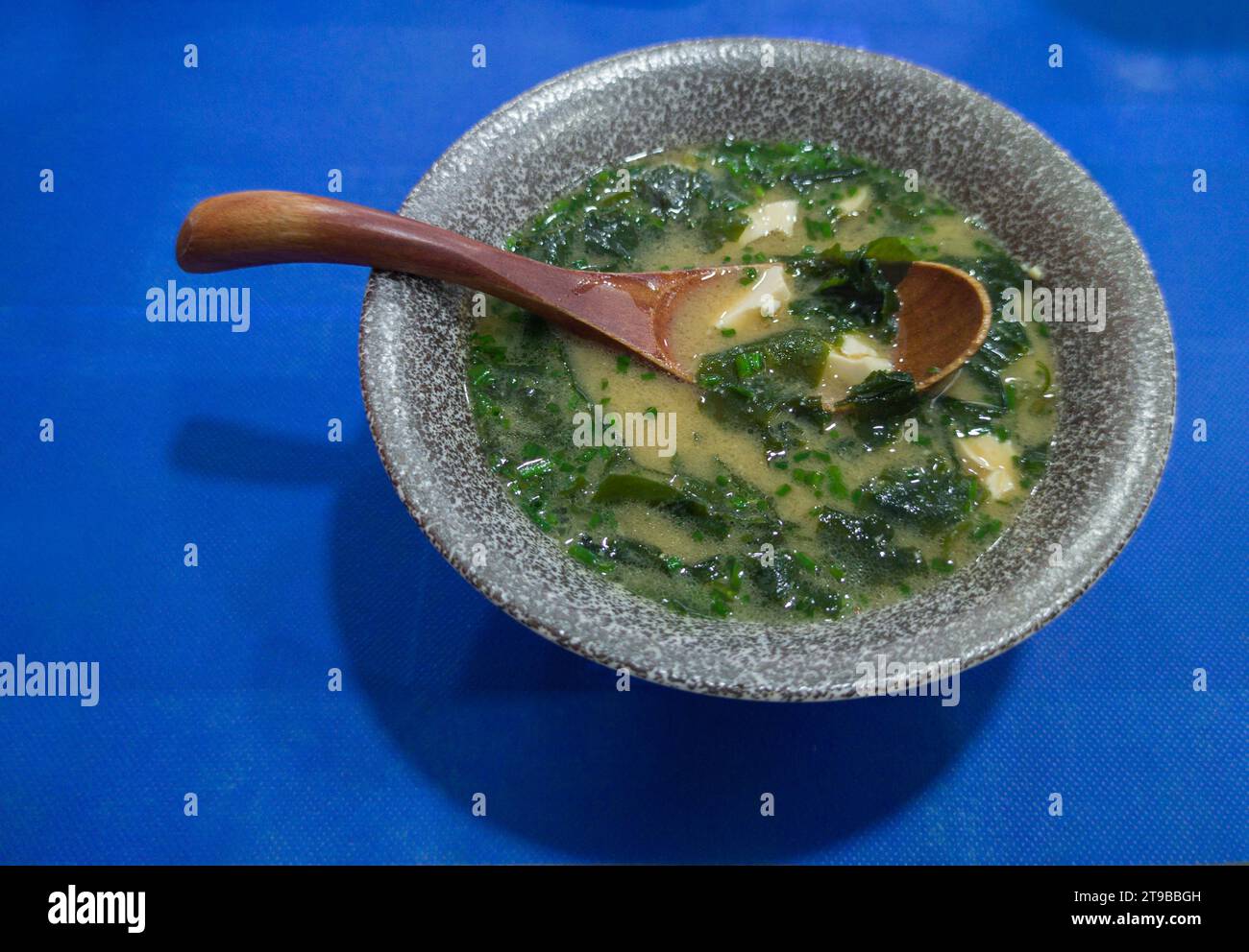 Zuppa di miso con alghe e tofu. Cucchiaio di legno su recipiente grigio Foto Stock