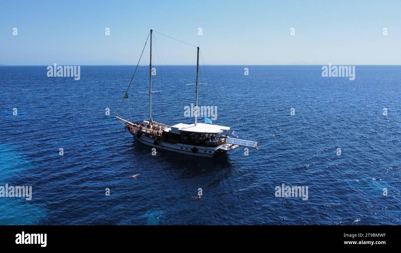 Barca a vela e catamarano in Grecia; acqua cristallina, splendidi colori e sfumature di blu. Sullo sfondo l'isola Foto Stock