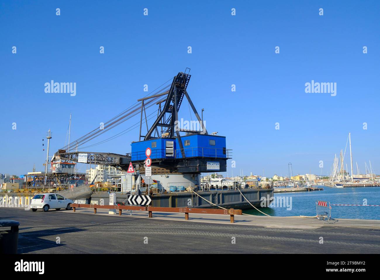 2023 luglio Rimini, Italia: Primo piano della gru blu nel porto di Rimini attraverso le barche e le navi nel porto Foto Stock